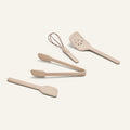 Four beige Mini Utensil Essentials—spatula, tongs, slotted turner, and whisk—are arranged on a plain light background.